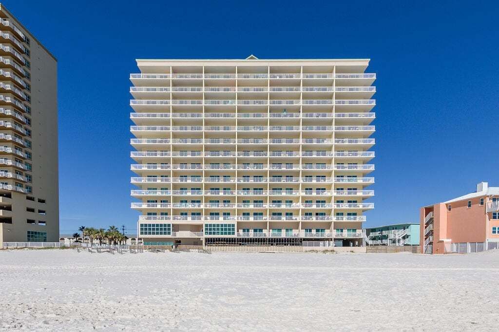 Een meerlaags hotel met een gelijkmatige gevel, talloze balkons en een plat dak.