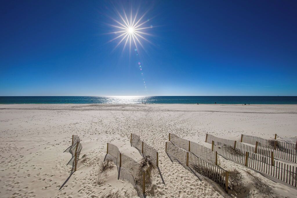 Een strand met een heldere lucht en een felle zon.