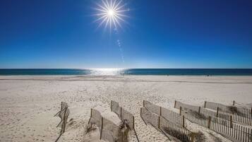 Een strand met een heldere lucht en een felle zon.