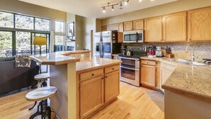 Una cocina moderna con armarios de madera, electrodomésticos de acero inoxidable y encimera de granito.
