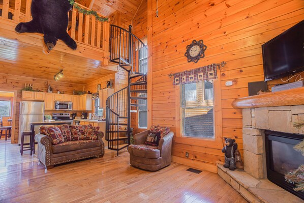 Cozy cabin interior with a spiral staircase, comfortable seating area, and a fireplace.