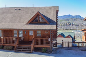 Relax on the inviting porch with a bench and chair, surrounded by serene mountains.