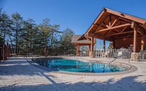 Relax by the pool surrounded by a lodge with a cozy atmosphere and shaded seating area.