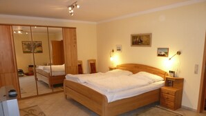 Ein Schlafzimmer mit einem großen Bett, einem Holzschrank, einem Fernseher und einem Bild an der Wand.