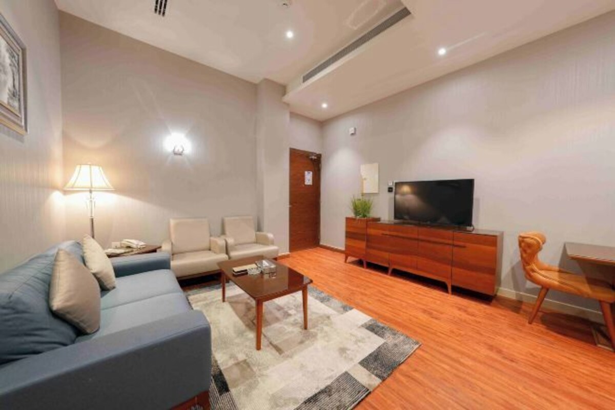 A modern living room with a sofa, coffee table, TV, and wooden furniture.