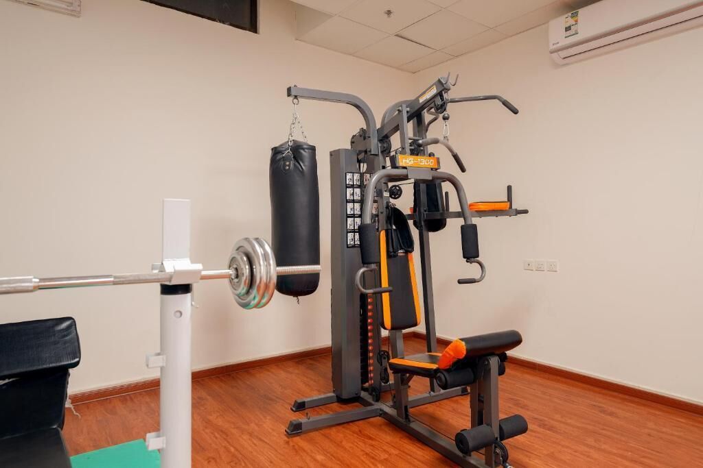 A gym with a squat rack, bench press, and a punching bag.