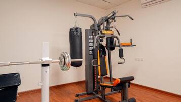 A gym with a squat rack, bench press, and a punching bag.