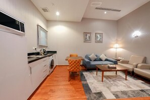 A compact living space with a kitchenette, a dining area, and a seating area with a sofa and a coffee table. - Celine Home Al Malqa (Riyadh)