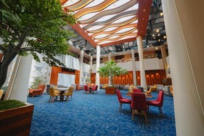 A spacious lobby with a high ceiling, multiple seating areas, and a central plant. - Celine Home Al Malqa (Riyadh)