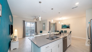 A modern kitchen with a central island, stainless steel appliances, and a ceiling fan. - (FA4830) Storey Lake Home 4/3 Private Pool & Free Waterpark (Kissimmee)