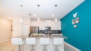 A modern kitchen with white cabinets, stainless steel appliances, and a teal accent wall. - (FA4830) Storey Lake Home 4/3 Private Pool & Free Waterpark (Kissimmee)
