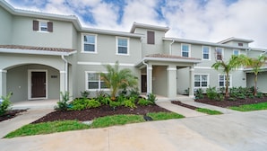 A row of two-story townhouses with a landscaped front yard, a driveway, and a clear sky. - (FA4830) Storey Lake Home 4/3 Private Pool & Free Waterpark (Kissimmee)