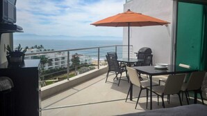A balcony with a table, chairs, and an umbrella.