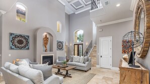 A spacious living room with a fireplace, a staircase, and a large mirror. - Private Pool-Golf Cart-Beach Service (Destin)