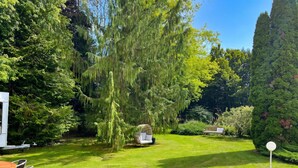 A well-maintained garden with a hanging chair, a bench, and a table with chairs.