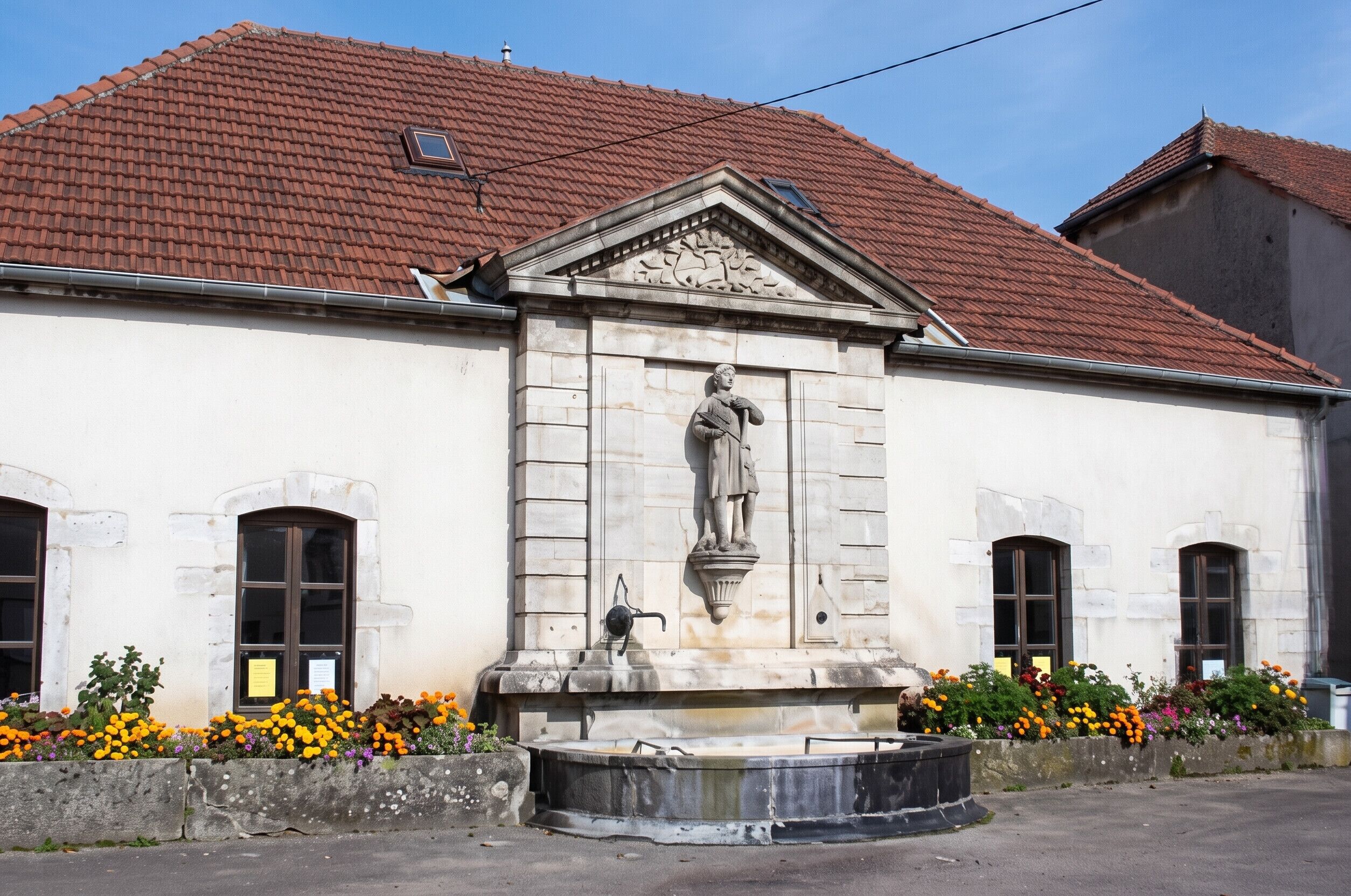 A building with a classical facade, a central statue, and a fountain.