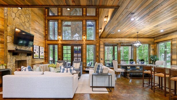 Un salón amplio con chimenea de piedra, ventanas grandes y un rincón de estar acogedor.