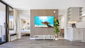Un salon moderne avec un grand téléviseur, une plante en pot et une vue sur la ville.