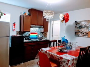 Una cocina con armarios de madera, un refrigerador, un microondas y un tostador. Hay una araña colgando del techo.