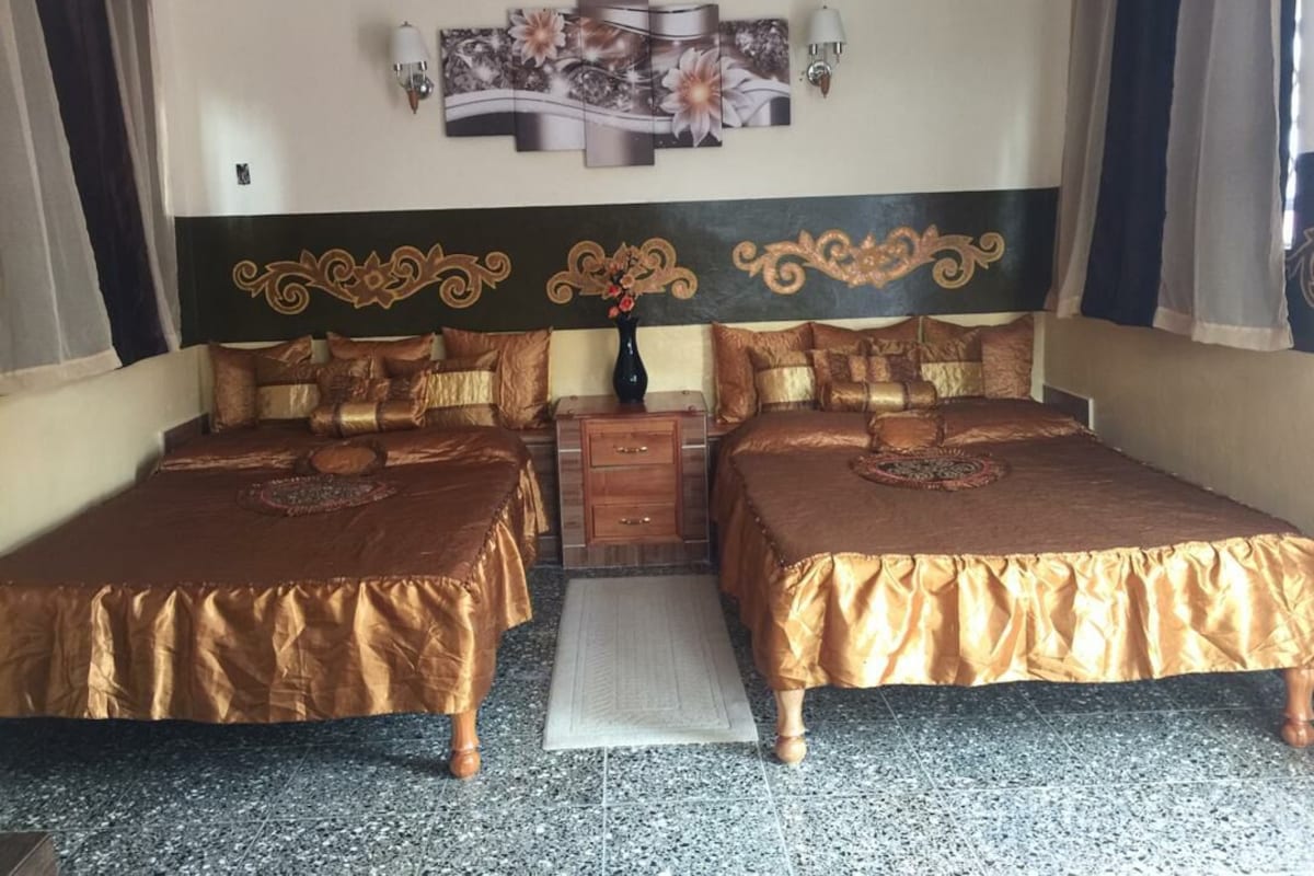 A double bed room with a headboard, a bedside table, and a decorative wall piece.