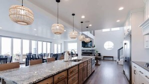 Una cocina amplia con una isla grande, armarios de madera e iluminación colgante.