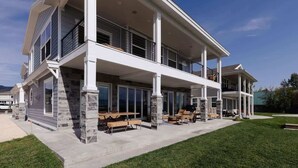 Una casa de dos plantas con un patio cubierto y mobiliario exterior.
