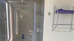 A modern bathroom with a glass shower enclosure, a towel rack, and a toilet paper holder. - Los Angeles Stay Inn (Quito)