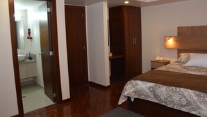 A bedroom with a bed, a nightstand, a bedside lamp, a wardrobe, and a bathroom visible through an open door. - Los Angeles Stay Inn (Quito)