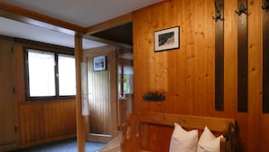 A wooden interior with a bench, a framed picture on the wall, and a door leading to another room. - Vacation cottage Greber, Austria (Mellau)