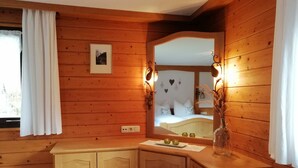 A wooden cabin room with a bed, a vanity with a mirror, and a small stool. - Vacation cottage Greber, Austria (Mellau)