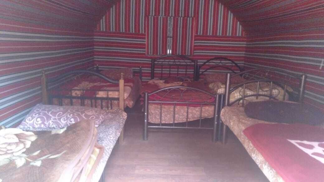 Ein Zimmer mit zwei Betten, gestreifte Wände und Holzboden.