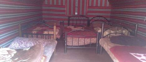 Ein Zimmer mit zwei Betten, gestreifte Wände und Holzboden.