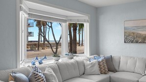 Una sala de estar con un ventanal grande, un sofá color beige y objetos decorativos en el alféizar.