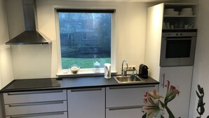 A modern kitchen with a large window, stainless steel appliances, and white cabinetry.