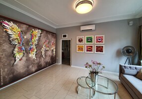 Un'ampia hall dal design moderno, con un grande murale, un tavolino in vetro e un divano.