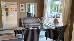 A hotel lobby with striped sofas, a vase with flowers, and framed artwork on the wall. - artHotel Bremen (Bremen)