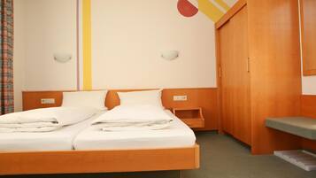 A hotel room with a wooden bed, a wardrobe, a bedside table, and a wall with a geometric design.