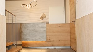 A modern reception area with a concrete reception desk, wooden paneling, a metal staircase, and a unique ceiling design. - Gasthof Adler (Hettingen)
