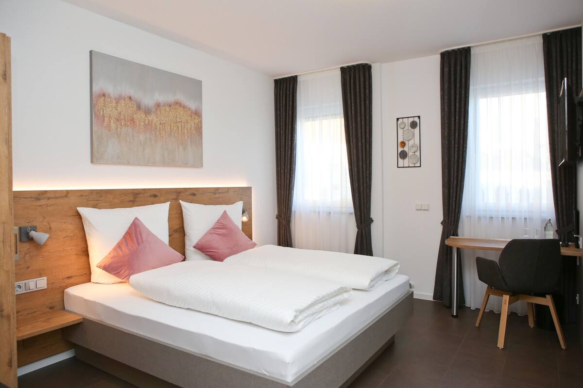 Quarto de hotel moderno com uma cama grande, uma mesa e uma cadeira.