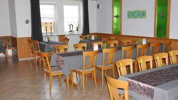Un comedor con sillas y mesas de madera, una barra con el menú, y vistas al exterior a través de amplias ventanas.