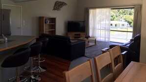 A modern living room with a sofa, chairs, a television, and a bookshelf. - Bay of Islands Gateway Motel (Paihia)