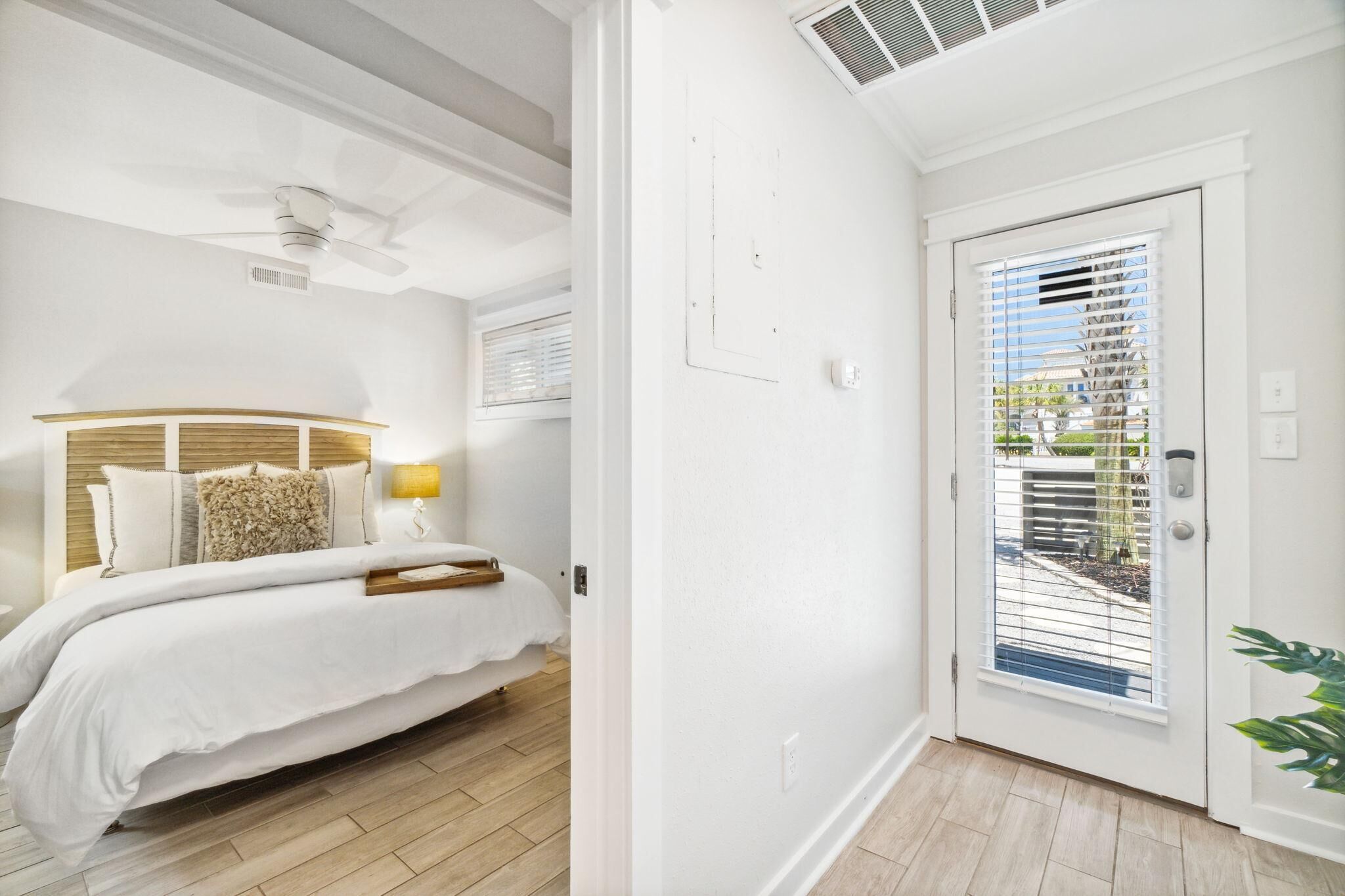 A bedroom with a bed, bedside table, lamp, and a ceiling fan.