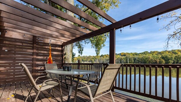 Una terraza de madera con mesa y sillas, con vista a un lago.