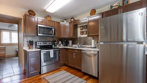 Una cocina moderna con electrodomésticos de acero inoxidable, armarios de madera y piso de baldosas.
