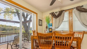 Un comedor con una mesa y sillas, vista a un lago y un árbol grande en el exterior.