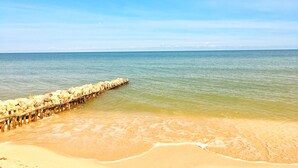 Une plage avec une jetée en bois qui s’avance dans l’eau.