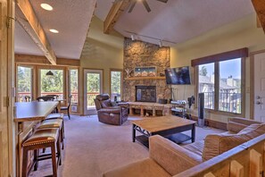 A spacious living area with a stone fireplace, leather furniture, and large windows offering views of the outdoors. - Townhome w/ Club Access on Shuttle Stop (Fraser)