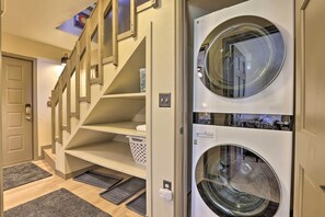 A laundry room with two front-loading washing machines, a wooden staircase, and a door leading to another room. - Townhome w/ Club Access on Shuttle Stop (Fraser)