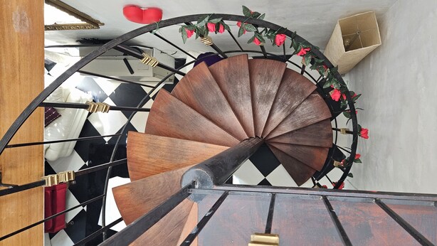 Eine Wendeltreppe mit Holzausstattung und Metallgeländern, verziert mit roten Rosen.