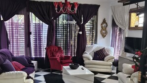 Ein Wohnzimmer mit Schachbrettboden, zwei weißen Sofas, einem roten Sessel und einem schwarzen Couchtisch.